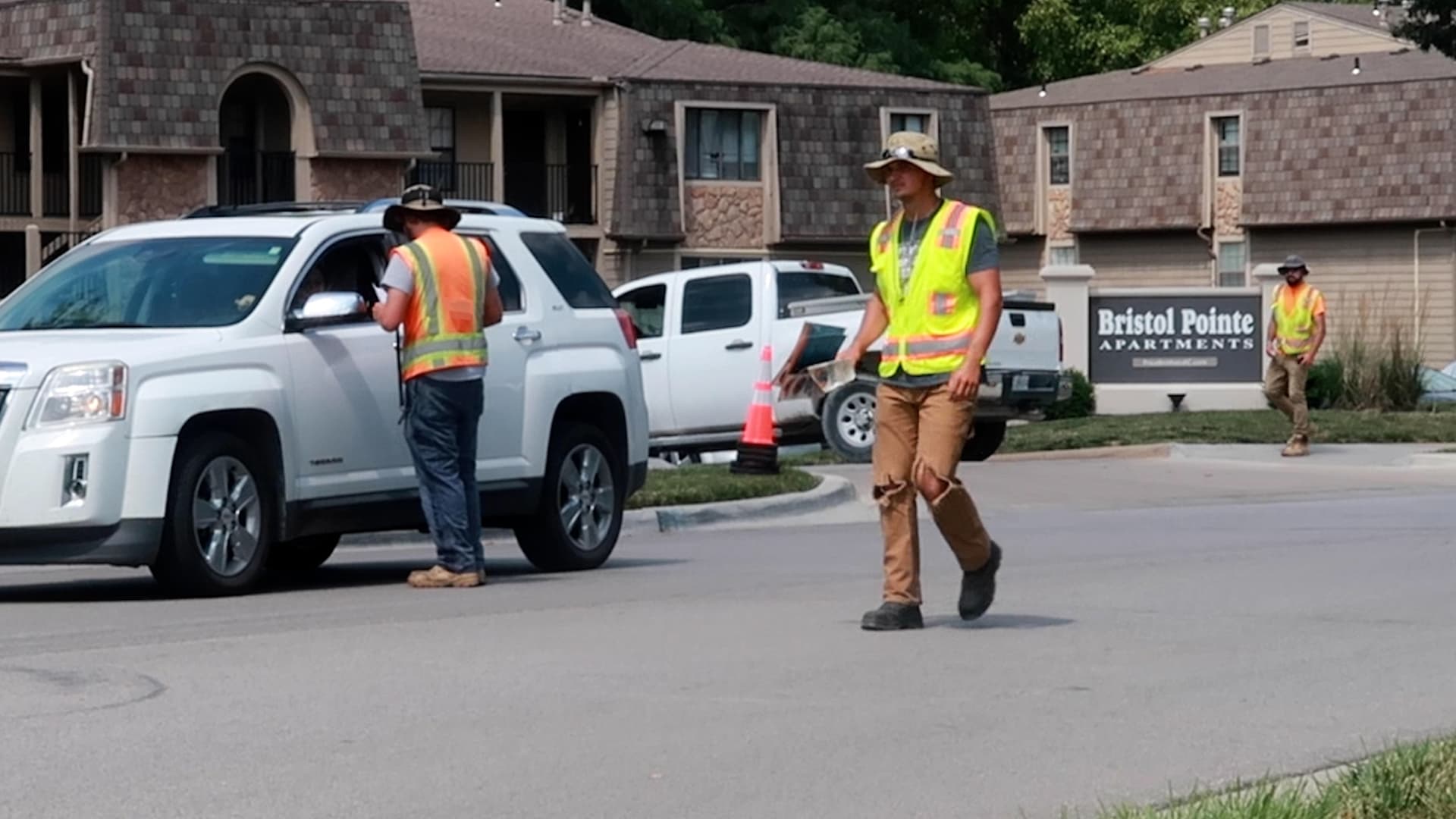 3 Flaggers Standing On a Roadway Speaking with Traffic.