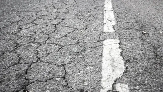 Severely cracked asphalt with a brittle white center line stripe